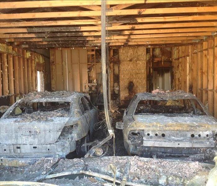 Aftermath of a garage fire. Two vehicles burnt down to the frame. All the drywall and insulation no longer intact.