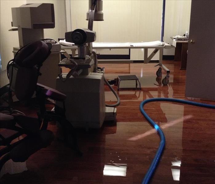 flooded office in a commercial building with doctor's equipment and a (blue) water extraction hose.